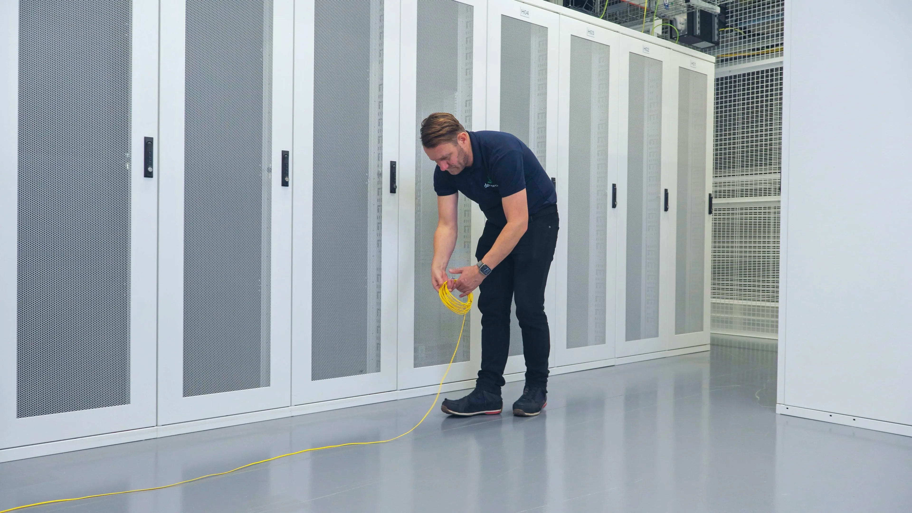DACPROS engineer coiling a cable run on the data centre floor — preparation before a full infrastructure migration.