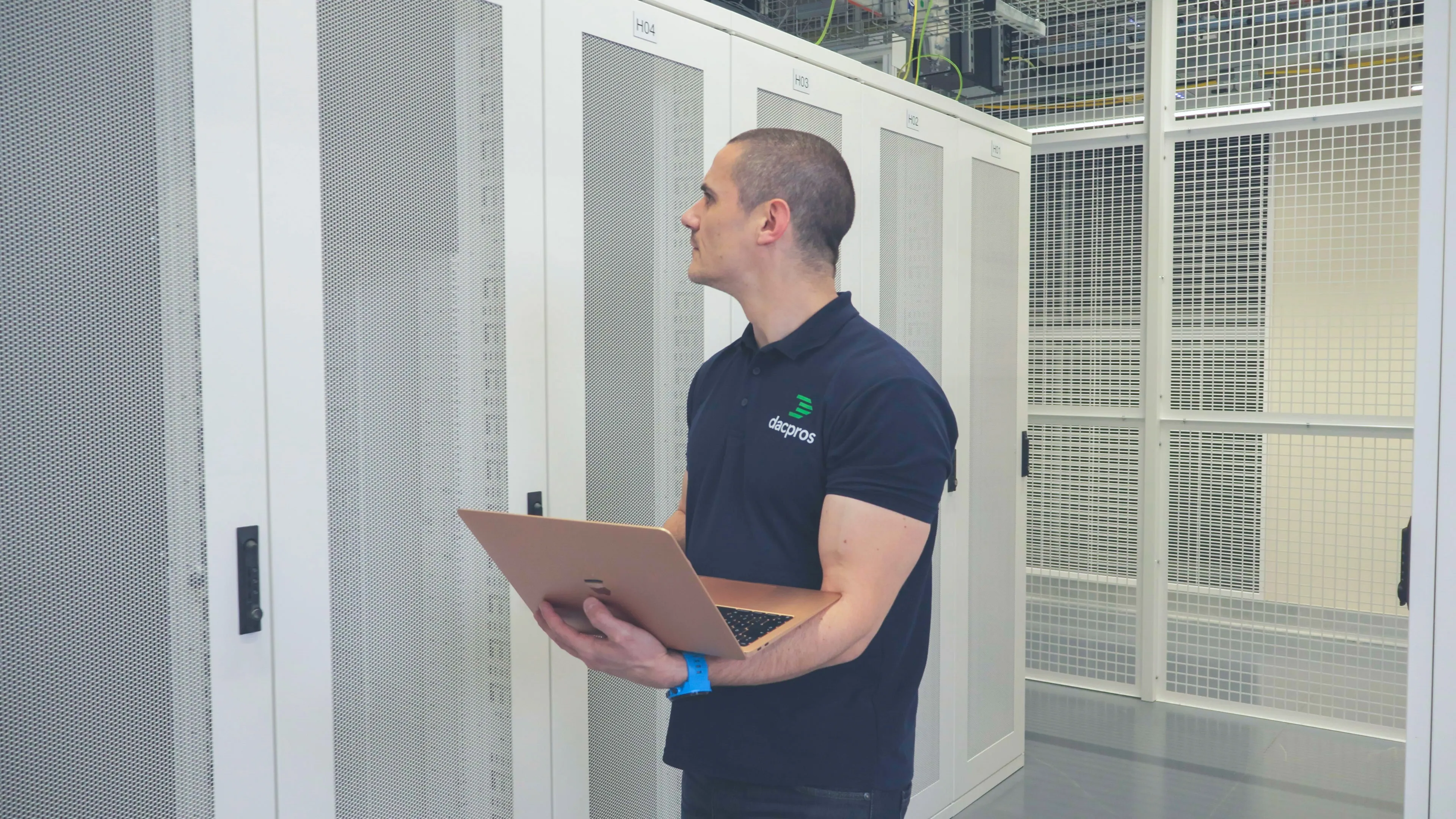 DACPROS engineer holding a laptop while inspecting server racks — on-site emergency response.